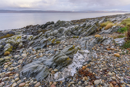Rocky shore near Pirnmill looking out across the Kilbrannan Sound to Mull of Kintyre, Isle of Arran, North Ayrshire, Scotland