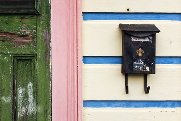 Detail of the facade of a colorful house in New Orleans, with an old mailbox with the fleur-de-lis