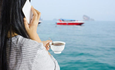 women hold cup of coffee and talking on mobile or smartphone at