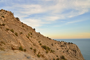 Fototapeta na wymiar Rocky hillside by the sea at sunset