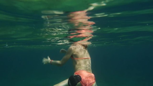 preteen girl swimming and diving in water, shot taken with underwater camera underneath surface.
