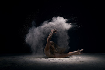 Gymnast in ecru bodysuit in cloud of white dust