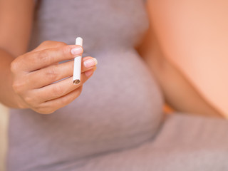 Pregnant woman holding cigarette. What harm baby, concept.