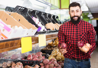 Man shop assistant demonstrating onions