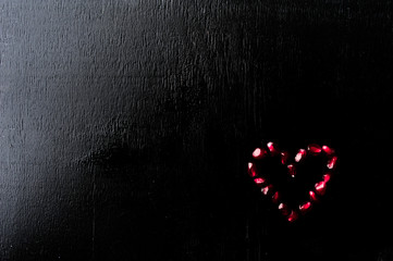 Delicious pomegranate fruit heart shape on black background