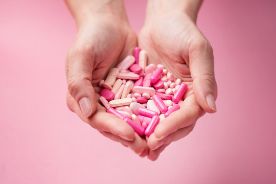 both hands holding bunch of pink pills