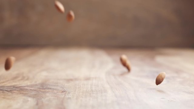 almonds falling in slow motion on wooden table, 180fps prores footage