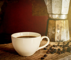 Coffee cup with moka pot coffee maker in the background. Soft light effect added for morning light.