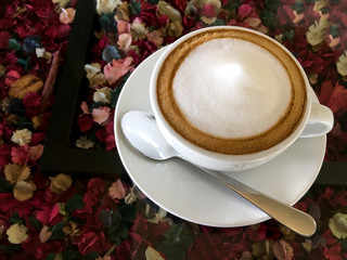 Hot coffee cappuccino on table with colorful dried flower backgr