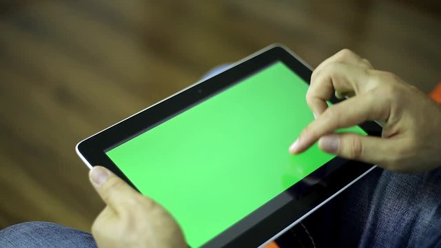 A man holding a tablet computer with a green screen. Man with the tablet. Male hand operated tablet computer with a green screen for your content. 