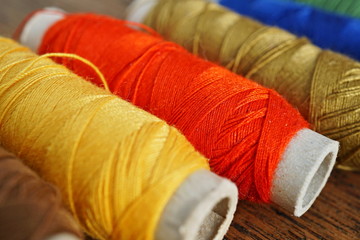 Row of colorful spools with yellow, brown, green, red and blue threads used for sewing as a symbol of housework, needlework and handwork 