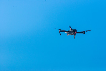 Fototapeta na wymiar Small modern drone hovering against blue sky