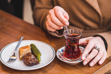 Fototapeta na wymiar Traditional tea with turkish delights. Woman's hand stirs sugar