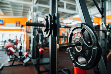 Interior gym with sports equipment. The bar with dumbbells in focus. sports background. Barbell...
