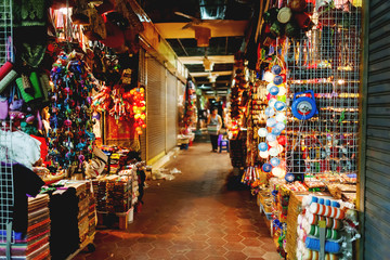 Obraz premium Sprzedaż pamiątek na rynku, Siem Reap, Kambodża. Kolorowe ręcznie robione koszule, szaliki, sukienki i tkaniny z różnymi złotymi typowymi azjatyckimi wzorami.