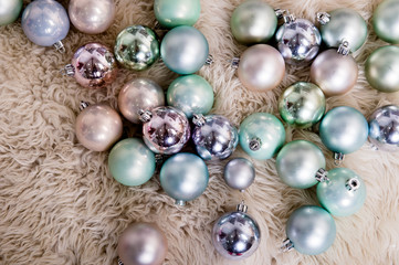 Christmas decorations in pastel shades and silver lying on sheepskin