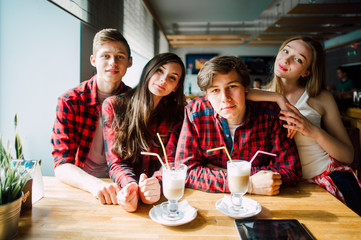 Group of young friends hanging out at a coffee shop. Young men and women meeting in a cafe having fun and drinking coffee. Lifestyle, friendship and urban life concepts.