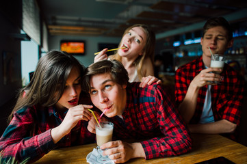 Group of young friends hanging out at a coffee shop. Young men and women meeting in a cafe having fun and drinking coffee. Lifestyle, friendship and urban life concepts.
