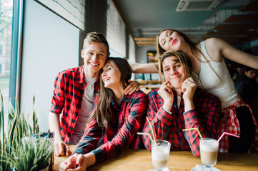 Group of young friends hanging out at a coffee shop. Young men and women meeting in a cafe having fun and drinking coffee. Lifestyle, friendship and urban life concepts.