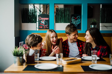 Group of young friends hanging out at a coffee shop. Young men and women meeting in a cafe having fun and drinking coffee. Lifestyle, friendship and urban life concepts.