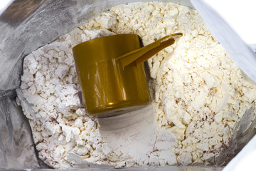 Bag and heap of vanilla chocolate whey protein. Nutrition for fitness and bodybuilding for gaining muscles. Full brown scoop inside. white background.