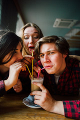 Group of young friends hanging out at a coffee shop. Young men and women meeting in a cafe having fun and drinking coffee. Lifestyle, friendship and urban life concepts.