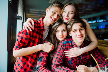 Group of young friends hanging out at a coffee shop. Young men and women meeting in a cafe having fun and drinking coffee. Lifestyle, friendship and urban life concepts.