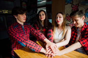 Group of young friends hanging out at a coffee shop. Young men and women meeting in a cafe having fun and drinking coffee. Lifestyle, friendship and urban life concepts.