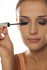 Fototapeta premium young woman applied mascara to her lashes