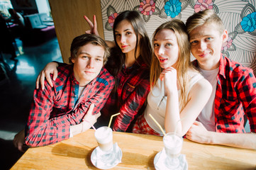 Group of young friends hanging out at a coffee shop. Young men and women meeting in a cafe having fun and drinking coffee. Lifestyle, friendship and urban life concepts.
