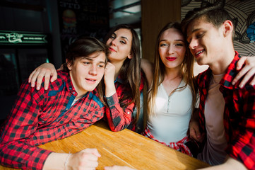Group of young friends hanging out at a coffee shop. Young men and women meeting in a cafe having fun and drinking coffee. Lifestyle, friendship and urban life concepts.