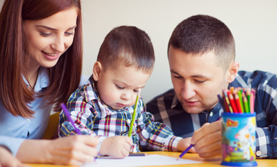 Young happy family with toddler boy playing together at home