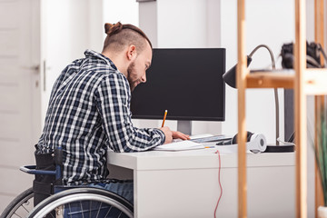 Obraz premium Concentrated handicapped man making notes
