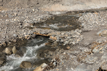 Fototapeta premium pedestrian bridge over the mountain stream from a stone
