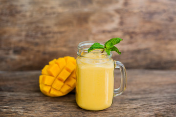 Mango smoothie in a glass Mason jar and mango on the old wooden background. Mango shake.