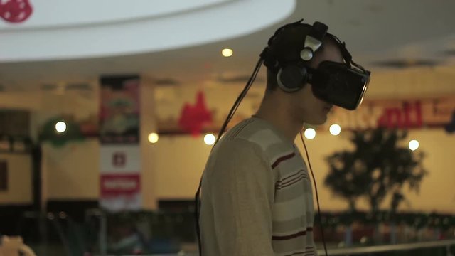 Close-up shot of a man in headphones getting experience in using VR-headset.