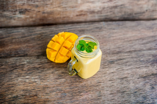 Mango smoothie in a glass Mason jar and mango on the old wooden background. Mango shake.