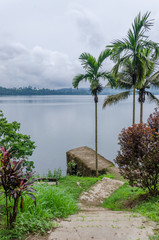 Concrete jetty, pathway and palms overlooking Barombi Mbo crater lake in Cameroon, Africa