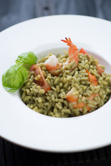 Closeup of spinach risotto with tiger shrimps and tomatoes