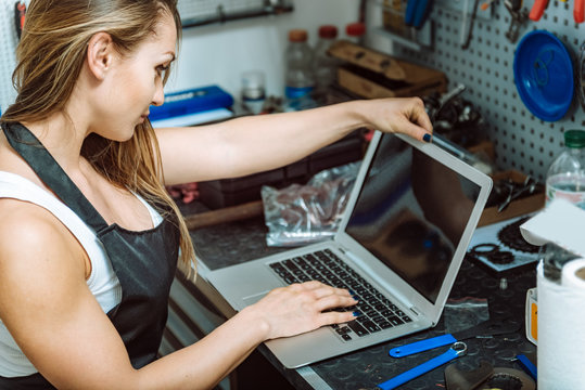 Young craftswoman working using a laptop in the garage