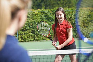 Female Tennis Coach Giving Lesson To Girl