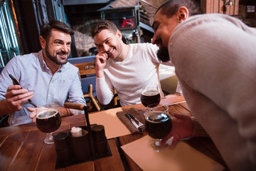 Cheerful positive men looking at the smartphone screen