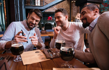 Pleasant bearded man pointing at the screen of his smartphone
