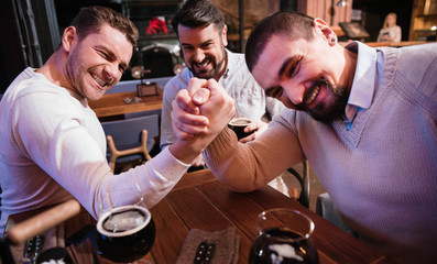 Cheerful pleasant men armwrestling in the pub