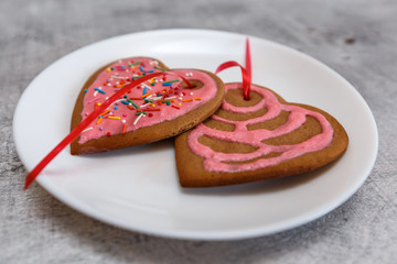 Chocolate gingerbread cookies heart shaped with red and pink icing on white plate