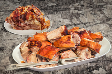 Plateful of Spit Roasted Pork Ham and Shoulder Slices Set on Old Cracked Flaky Wooden Garden Table