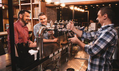 Cheerful bearded bar attender pouring a drink