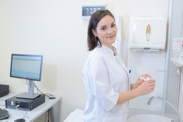 Lady in white coat washing her hands