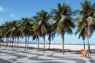 Fototapeta na wymiar Copacabana view with palm trees, famous sidewalk and a bicycle