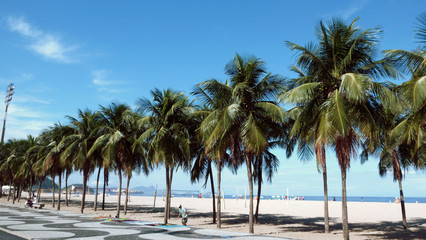 Fototapeta na wymiar Copacabana palm trees, sidewalk and a sarong vendor